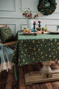 Macro detail of dark green Christmas tablecloth with gold snowflake and bell patterns