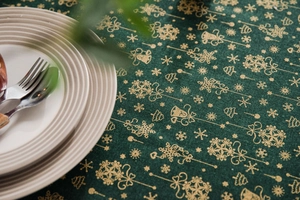 Detail of green Christmas tablecloth showing gold-stamped festive patterns and fabric texture