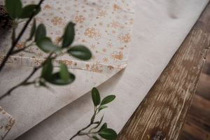 Close-up of golden Christmas bells and snowflake print on linen table runner