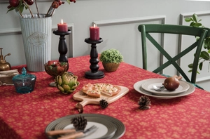 Close-up of red Christmas tablecloth with golden floral print on a festive dining table