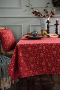 Close-up of red Christmas tablecloth with golden snowflake and bell prints on cotton linen