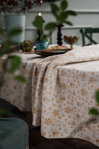 Close-up of cotton linen tablecloth featuring gold Christmas trees and snowflake patterns