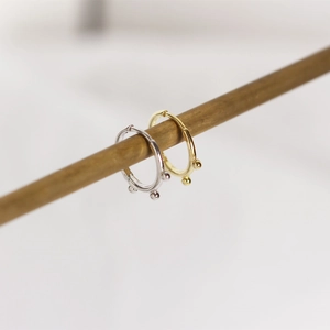 Close-up of gold and silver S925 sterling silver hoop earrings with small bead accents