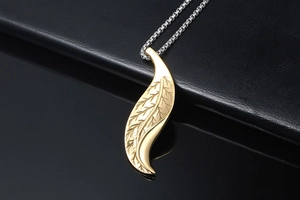 Detailed close-up of golden leaf pendant with intricate feather texture on black leather