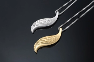 Macro view of gold and silver leaf pendants showing detailed veins on black background