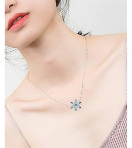 Detailed view of silver snowflake pendant necklace with crystals on model's neckline