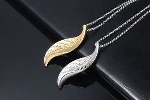 Detailed close-up of gold and silver feather pendants with fine engraved textures on chain