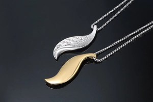 Close-up of gold and silver leaf pendants with intricate textures on box chains