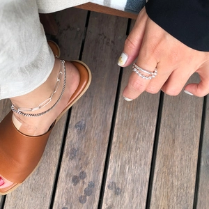 Close-up of stacked 925 sterling silver anklets and a double-layer beaded ring on a model