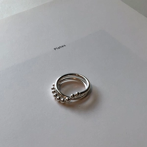 Detailed close-up of double-layered silver bead rings on a clean minimalist backdrop