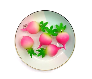 Top view of five realistic pink radish pendants with green leaves in a white ceramic bowl