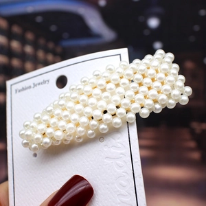 Detailed view of elegant white pearls on a gold-tone bobby pin clip set on card