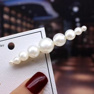 Macro view of gradient white pearls set on a golden metal minimalist hair clip