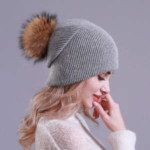 Detail of grey ribbed knit beanie with a fluffy brown pom pom shown on a female model