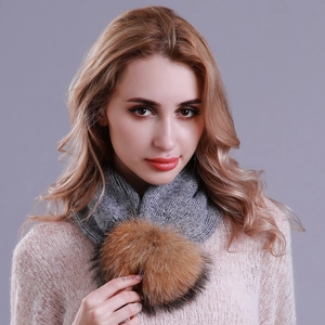 Detail of grey knitted winter neck warmer with a fluffy brown faux fur pom pom accent