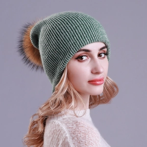 Detailed close-up of dark green ribbed knit beanie with a large bicolor faux fur pompom