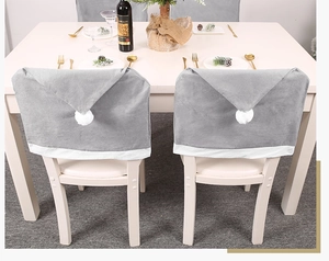 Detail of gray plush Christmas chair covers with white pom-poms on dining chairs
