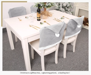 Detail of grey non-woven Christmas chair cover with white pom pom in a cozy dining setting