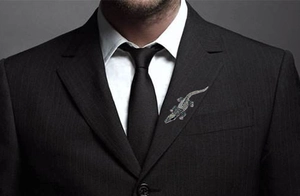 Detailed view of a sparkling crocodile brooch pinned on a black business suit lapel