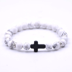 White turquoise beaded bracelet featuring a black cross pendant and silver spacers