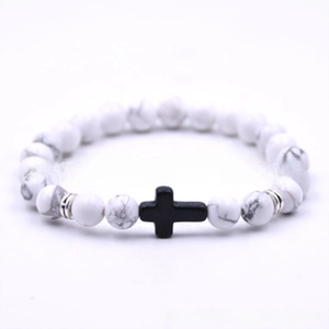 Macro view of white howlite beaded bracelet featuring a black matte cross and silver spacers