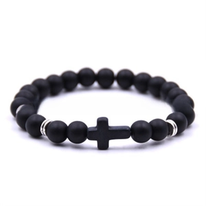 Macro shot of matte black stone beaded bracelet featuring a central cross and silver spacers