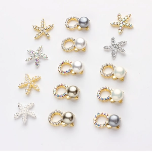Mix of metal starfish and pearl nail art charms with rhinestones on white background