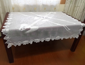 Detail of white lace Halloween shawl featuring human skeleton pattern and skull edge lace