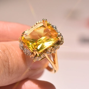 Close-up of a luxury gold ring featuring a large rectangular champagne stone and halo
