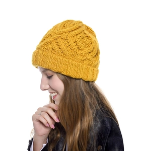 Detailed close-up of thick chunky knit texture on a mustard yellow beanie for winter