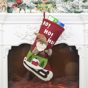 Red Christmas stocking with Santa Claus and HO HO HO print hanging by the fireplace
