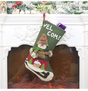 Green Christmas stocking with a 3D snowman and Welcome embroidery hanging on a fireplace