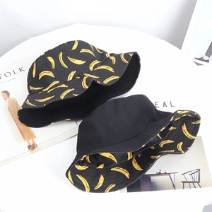 Flat lay of canvas bucket hats with yellow banana prints and a reversible black lining