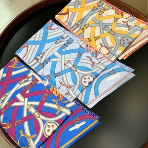Detail of folded twill silk scarves featuring classic equestrian belt and buckle prints