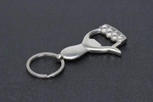 Macro shot of silver metal thumb shaped keychain bottle opener on textured background