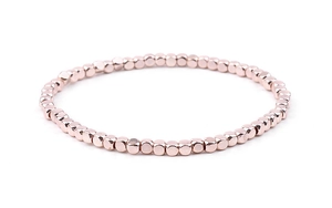Detail of rose gold stretch bracelet featuring metallic cube beads on a clean white background