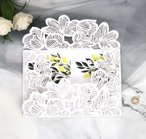 Macro detail of laser-cut white wedding invitation with elegant lemon leaf illustration