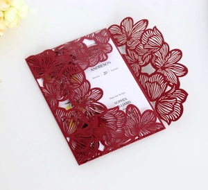 Detail of laser-cut burgundy wedding invitation with intricate floral patterns and inner card