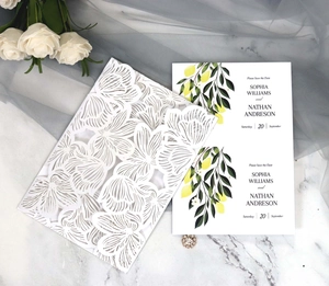 Detail of laser cut flower wedding invitation with lemon pattern card and white rose