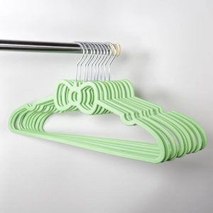 Detail of green plastic hangers with bow design and metal hooks on a laundry rod
