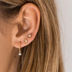 Detail of model wearing 18K gold earrings with cubic zirconia charms and studs