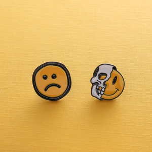 Detail of yellow enamel lapel pins with funny sad face and skull smile expressions