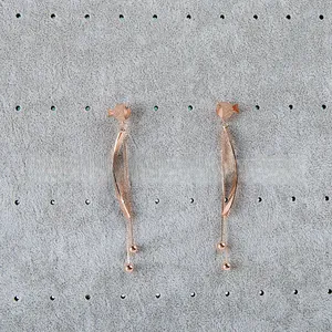 Detail view of rose gold fish tassel earrings on a velvet jewelry display stand