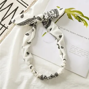 Detail of cream cotton headband with black paisley pattern and rabbit ear knot decoration