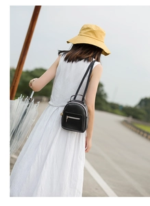Outdoor shot of a woman with a yellow sun hat wearing a black mini leather backpack