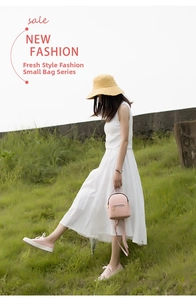 Close-up of a pink leather mini backpack with metal zippers on a model in a white dress