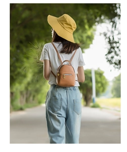 Outdoor shot showing a woman wearing a compact tan PU leather backpack with gold zippers