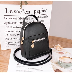 Detail of mini black PU leather backpack with gold zippers on a wooden desk setting