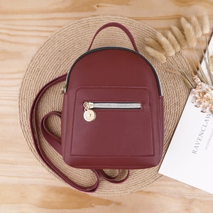 Burgundy PU leather mini backpack with gold zipper detail on a rustic straw mat