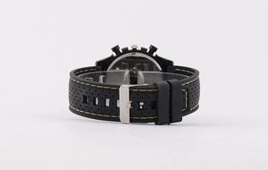 Detail of black perforated rubber watch strap with contrast yellow stitching and silver buckle